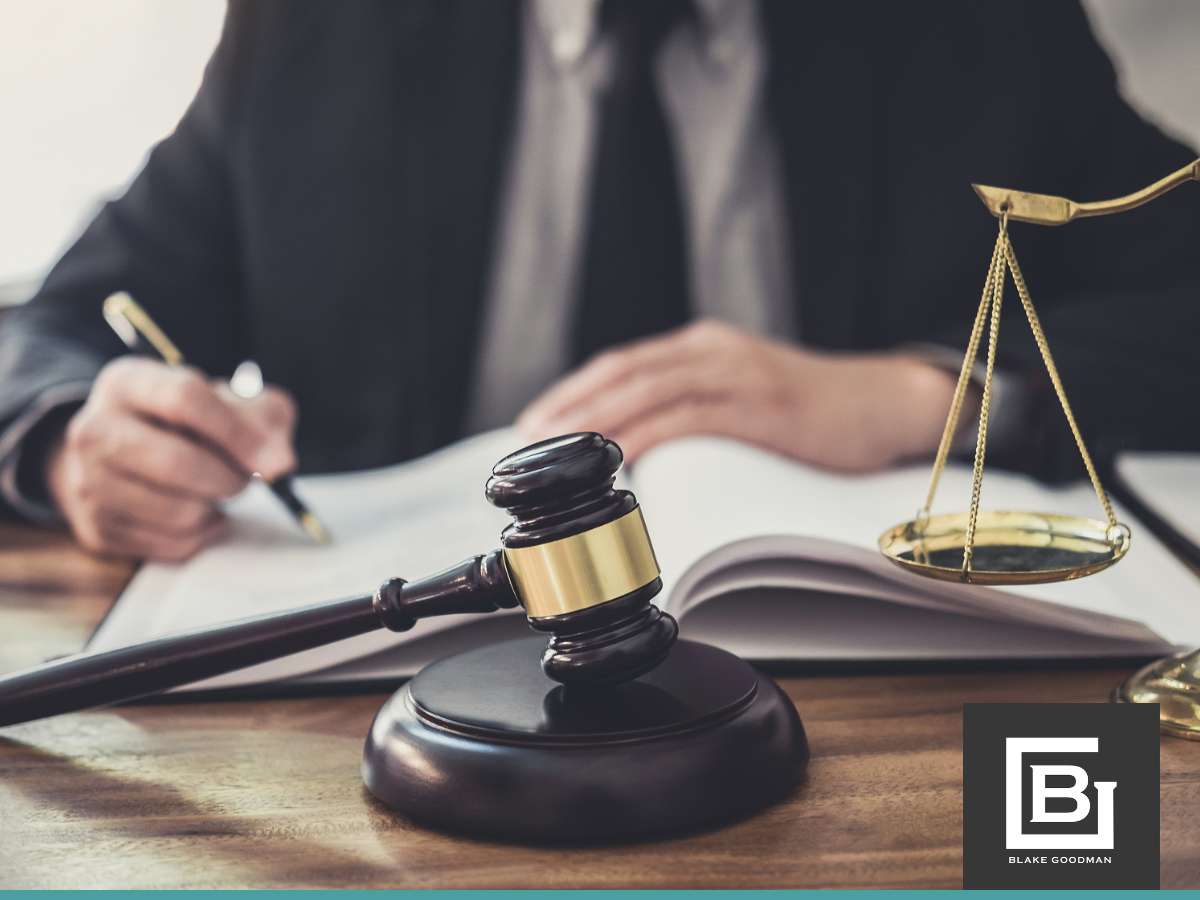 A lawyer signing documents, possibly related to mortgage applications, with a gavel and scales of justice on the desk