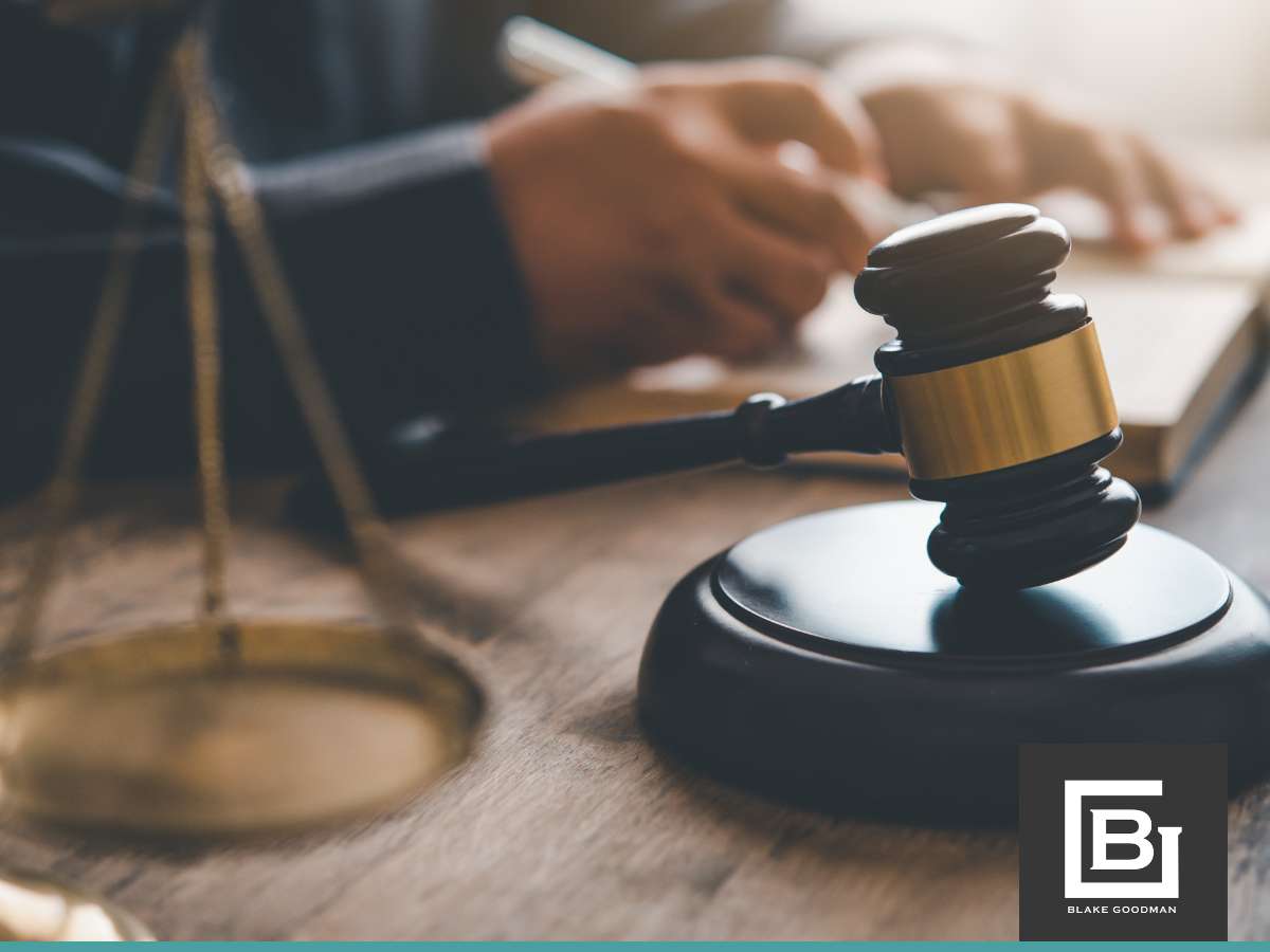 A gavel and a sound block on a desk with a blurry figure in the background, possibly a lawyer, writing on a document, symbolizing legal advice on loan modification vs. refinancing after bankruptcy.